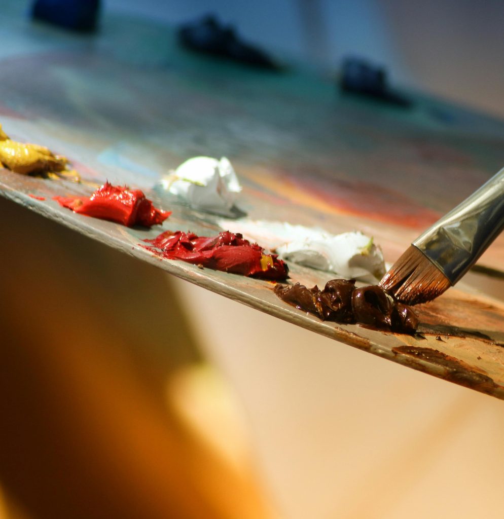 Vibrant artist palette with paint and brush creating colorful artwork.